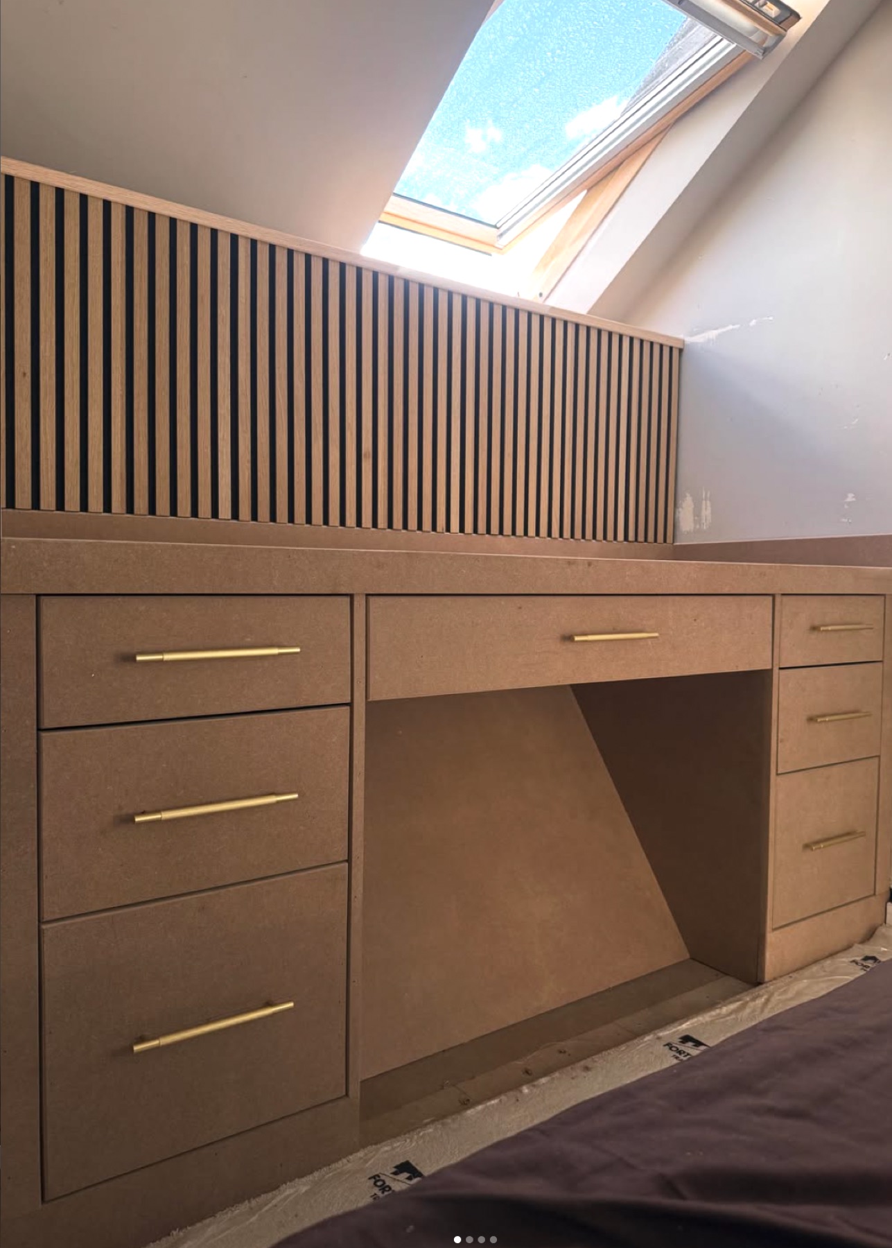 Built-in dressing table with drawers under a slatted feature wall