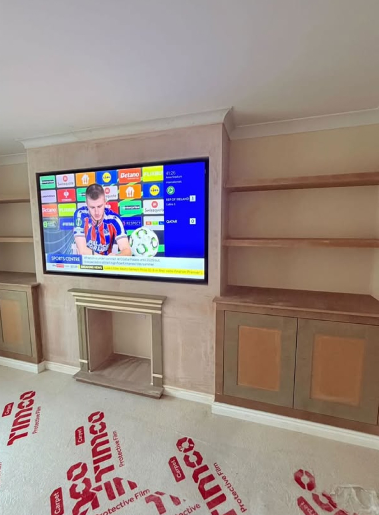 A media wall with Shaker-style cabinets, a bespoke hearth and an arched mantle, TV recessed above the fireplace