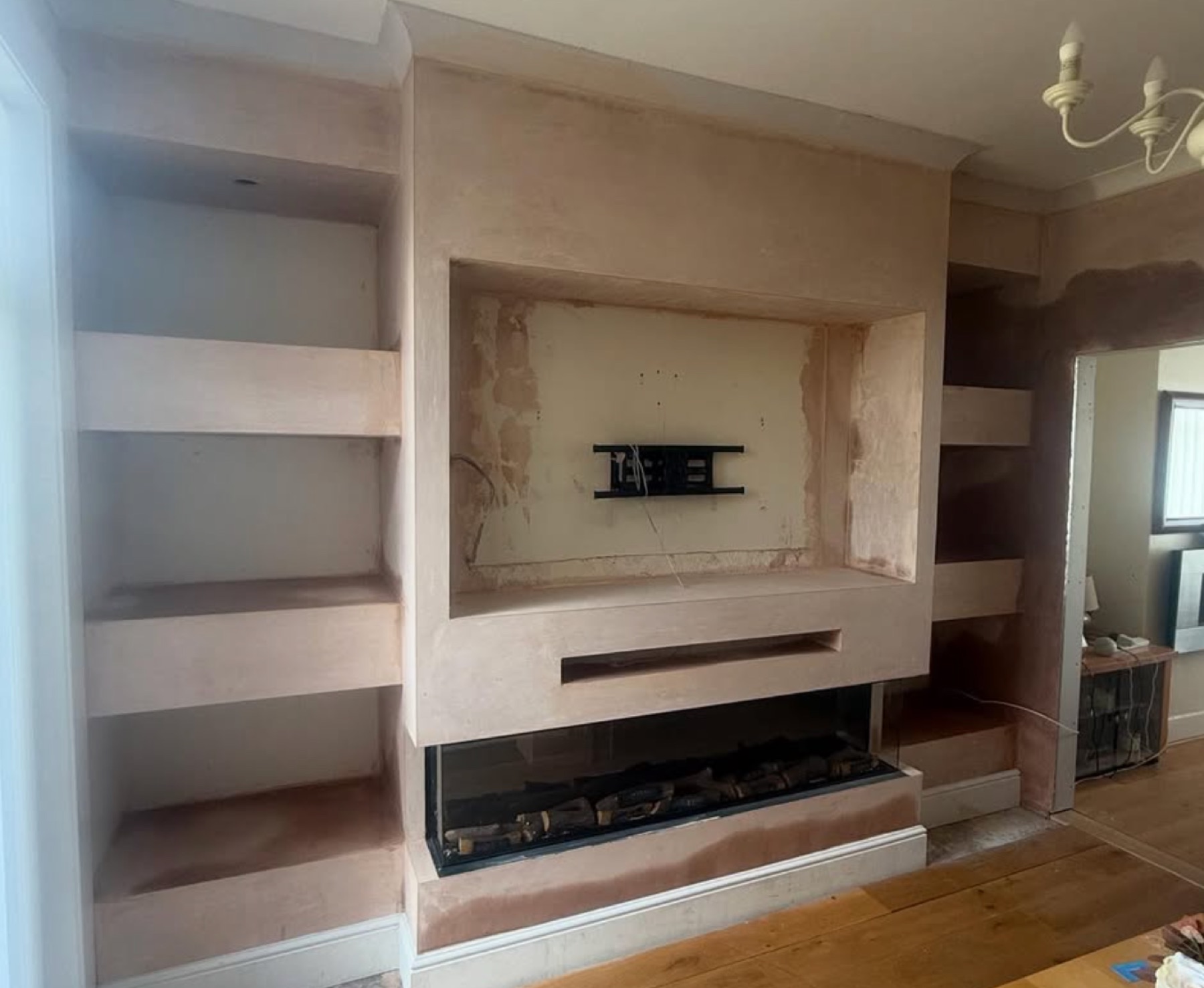 The media wall mid-build in bare plaster with the TV bracket mounted