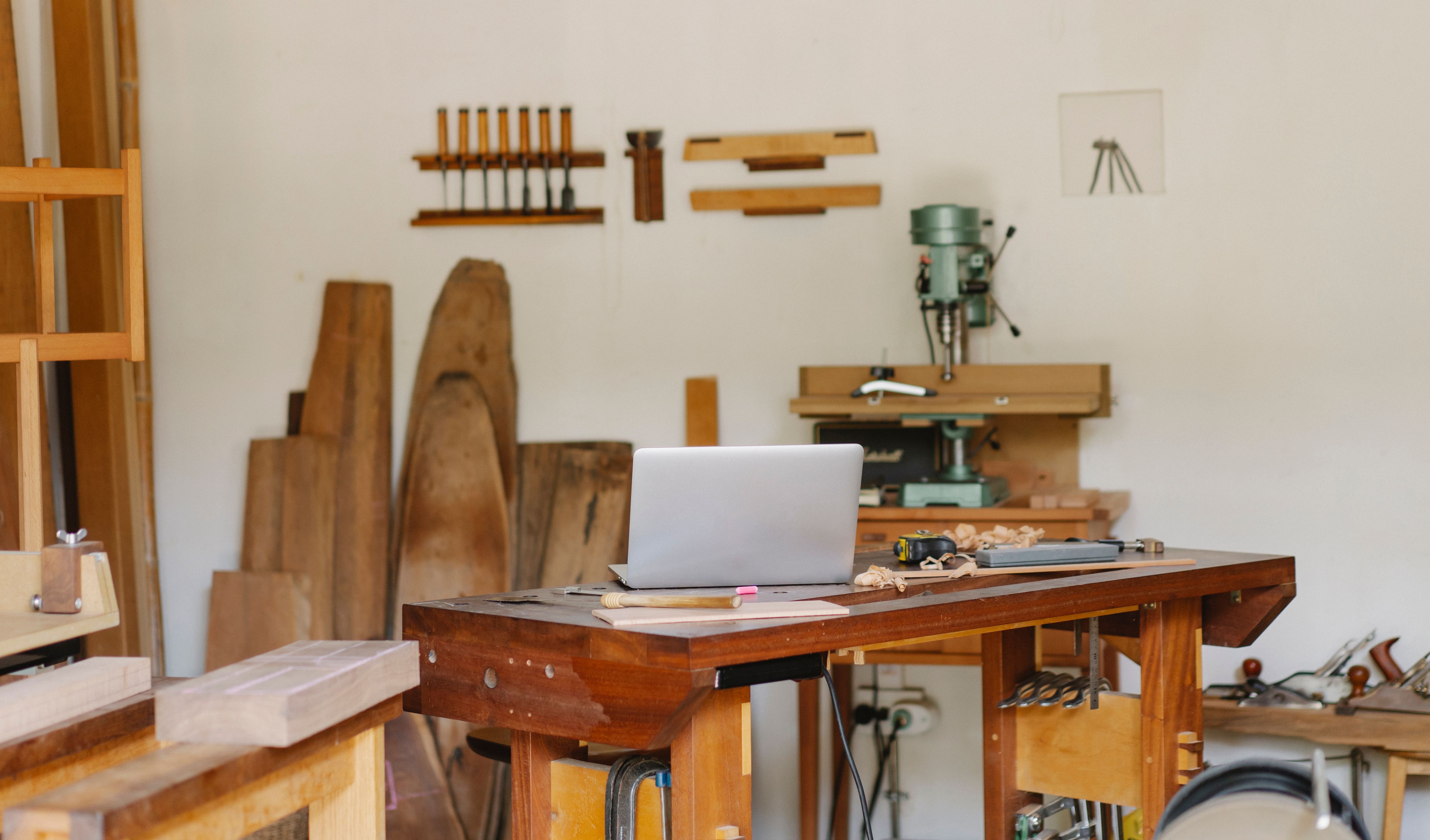 A joinery workshop bench with chisels, drill press, timber offcuts and hand tools